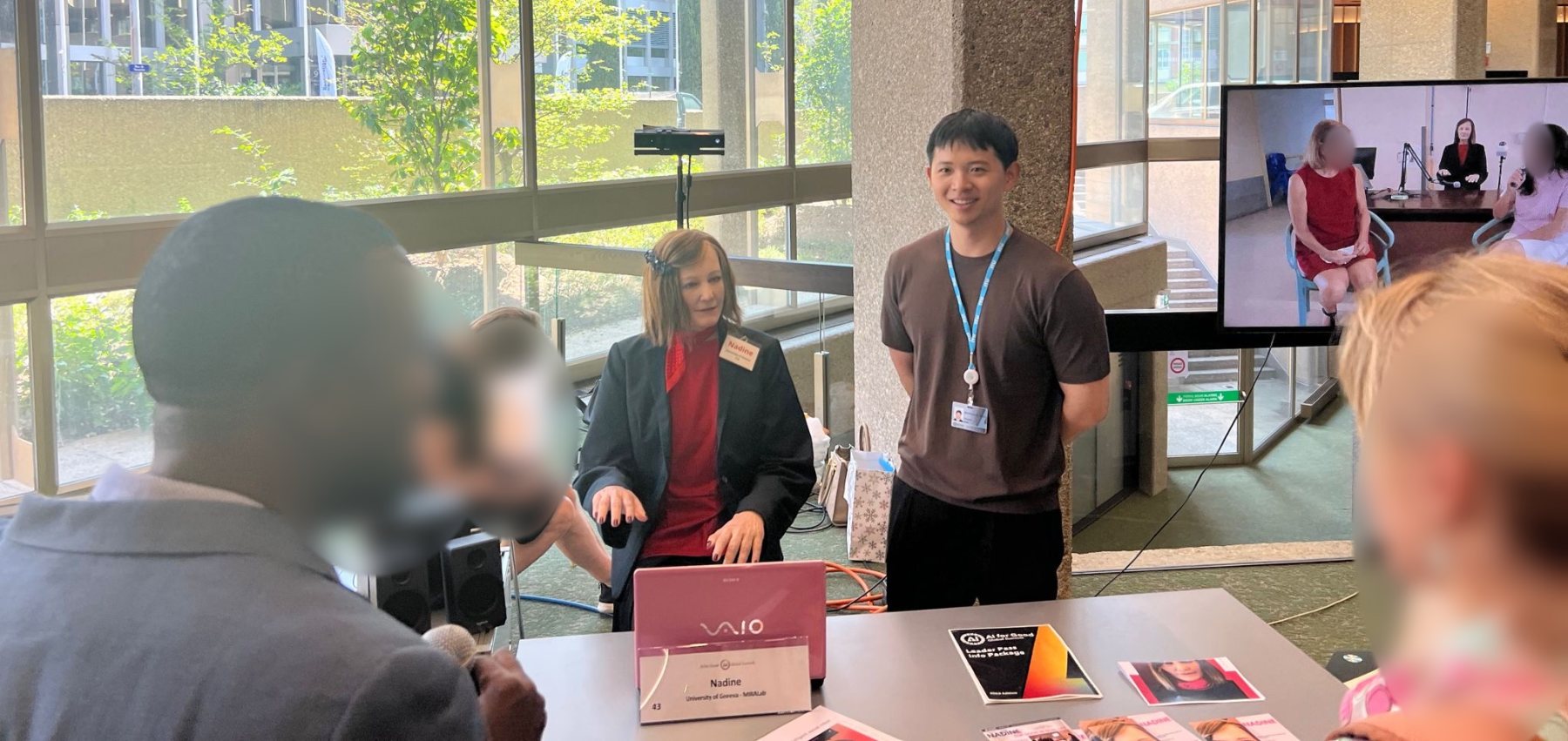 Hangyeol Kang standing next to the robot Nadine while a visitor talks to her with a microphone at an ITU event in Geneva