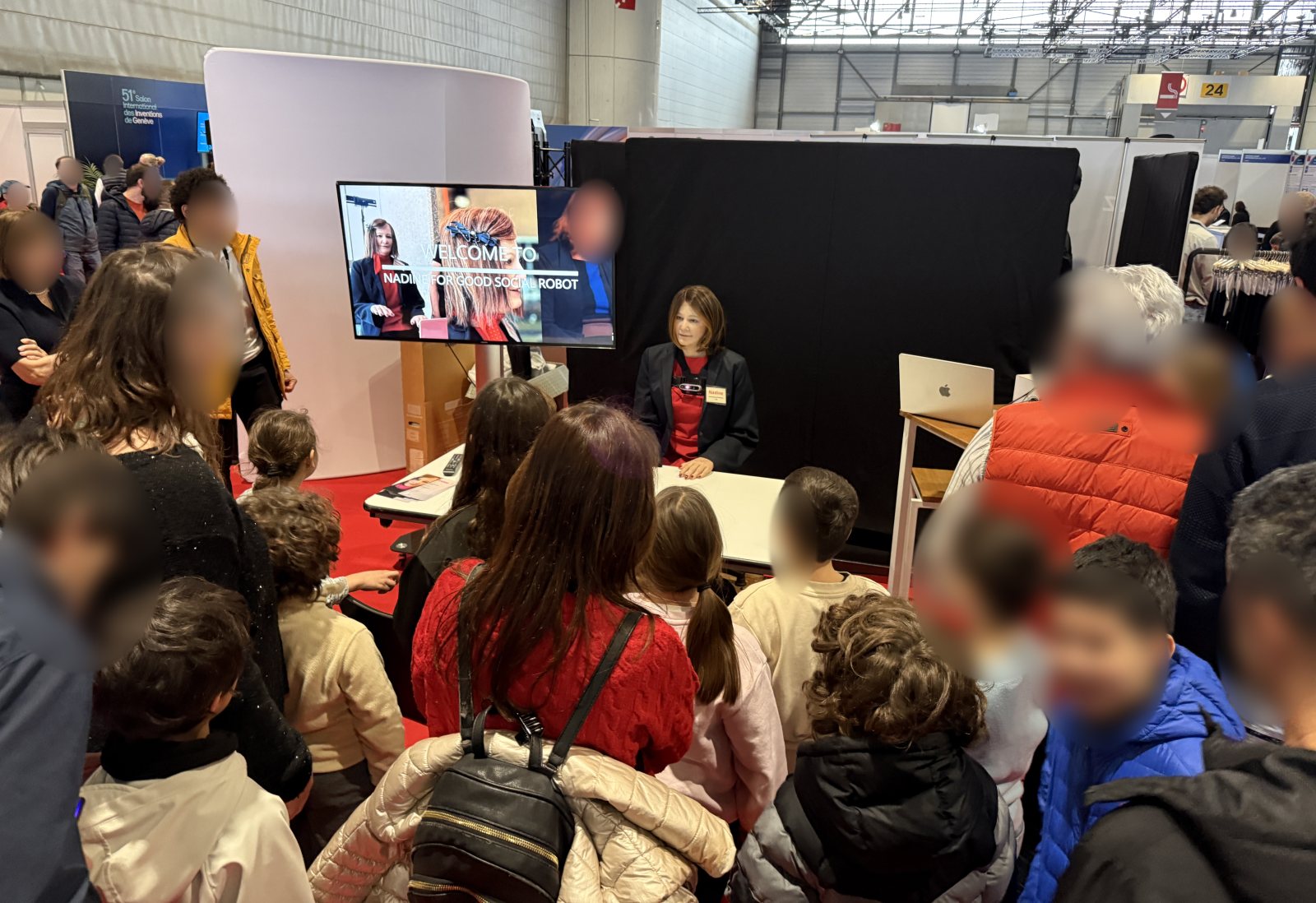 Children and families crowd around Nadine's booth at the Exhibition of Inventions in Geneva